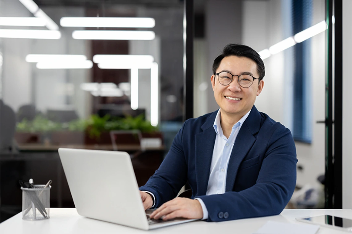 Man sitting at laptop smiling for camera