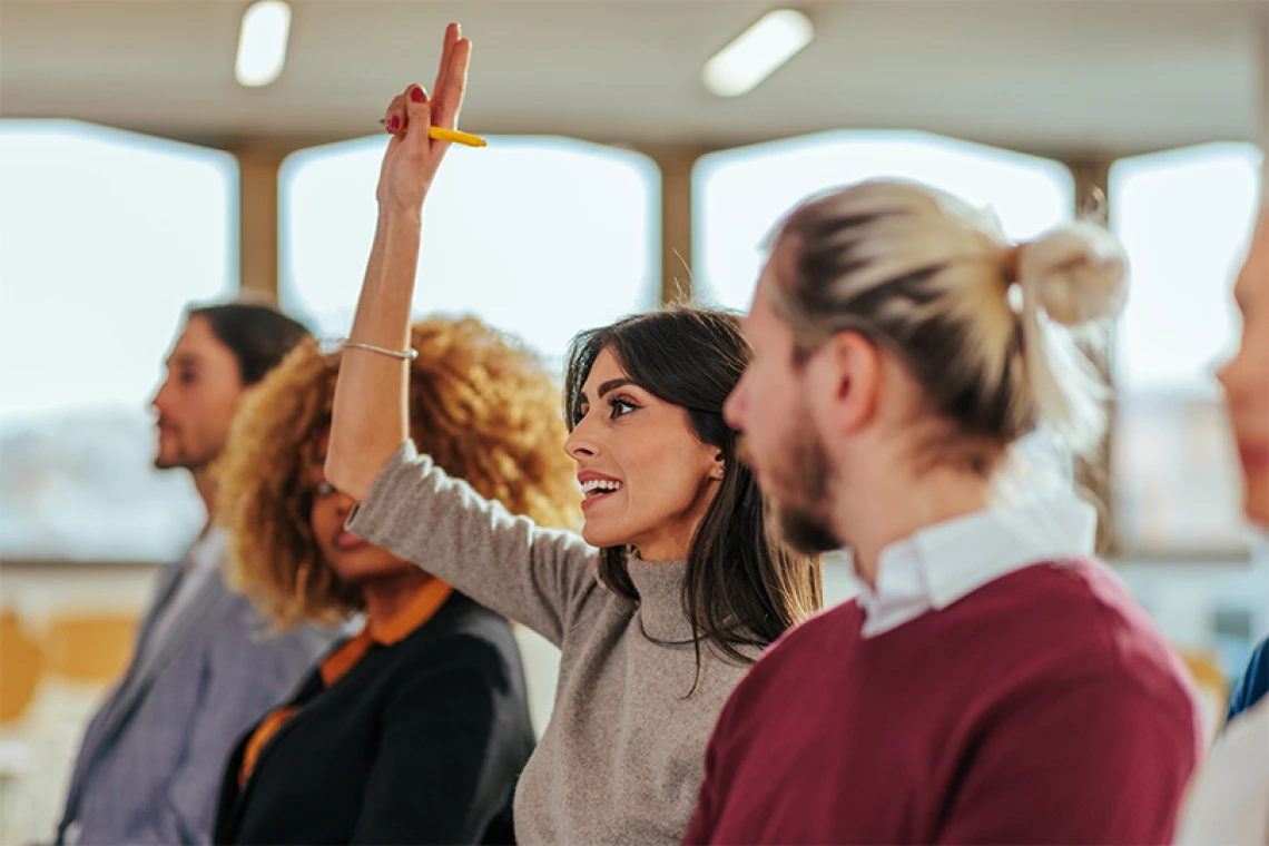 Person raising their hand inside a conference room