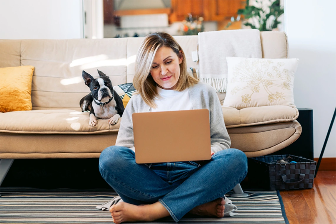 Person sitting on laptop on the floor in front of couch