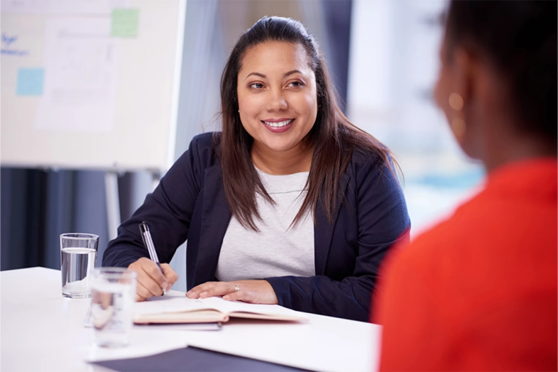 Person smiling while writing in notebook