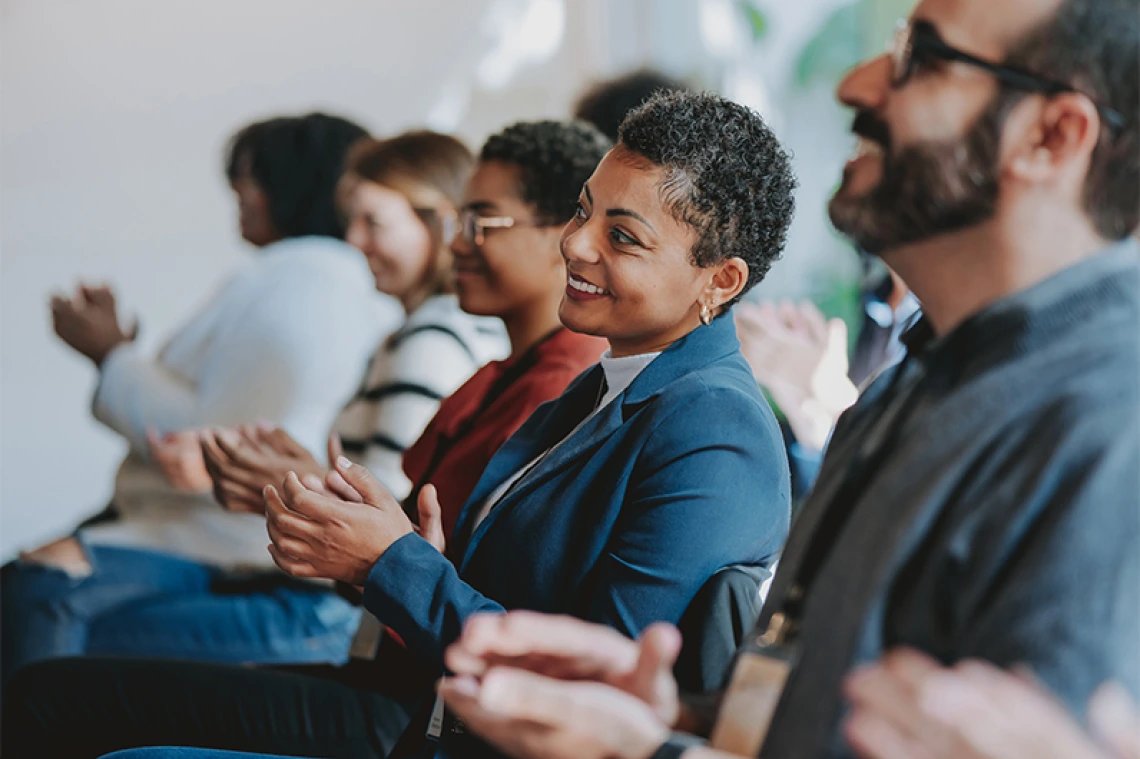 People smiling and clapping inside a meeting room