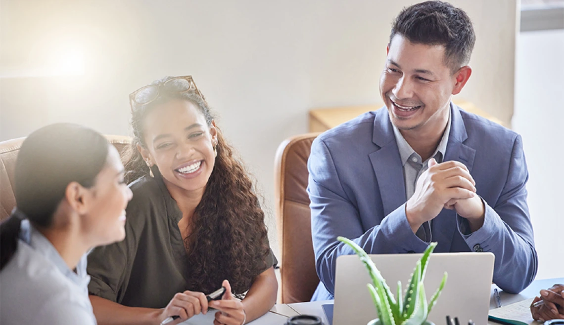 Group of young professionals smiling and talking together at a desk