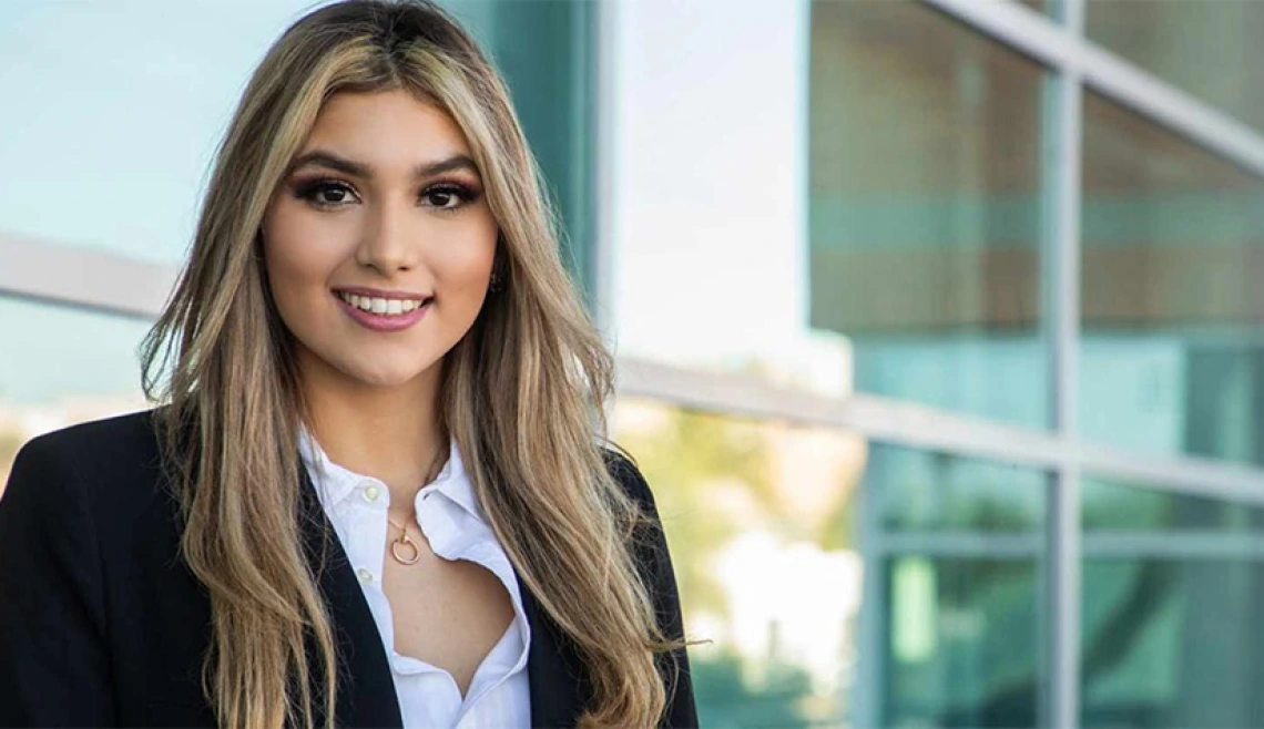 Person smiling while standing outside of a corporate building