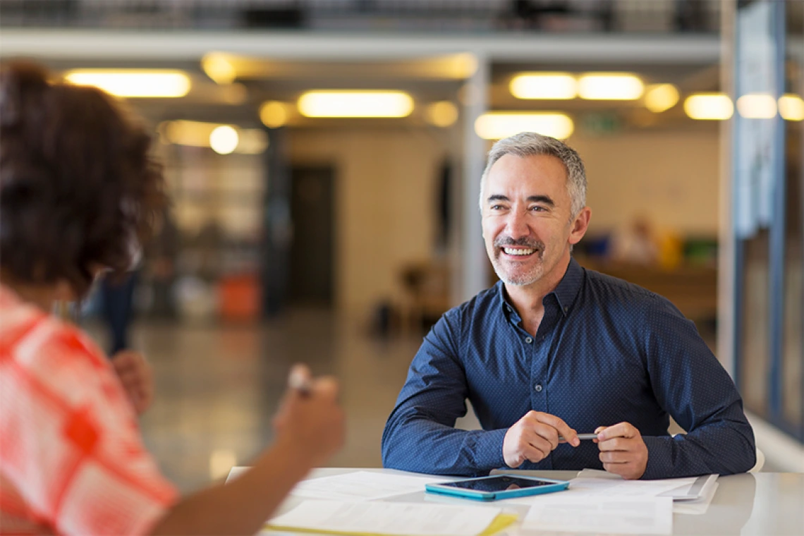 Man smiling while talking to another person at a table