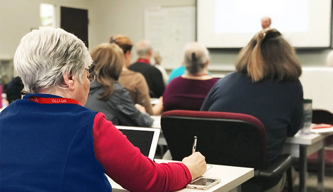 Over-the-shoulder shot of older person working in classroom setting