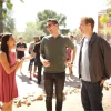 Three students talking outside on campus with more students and school building in the background